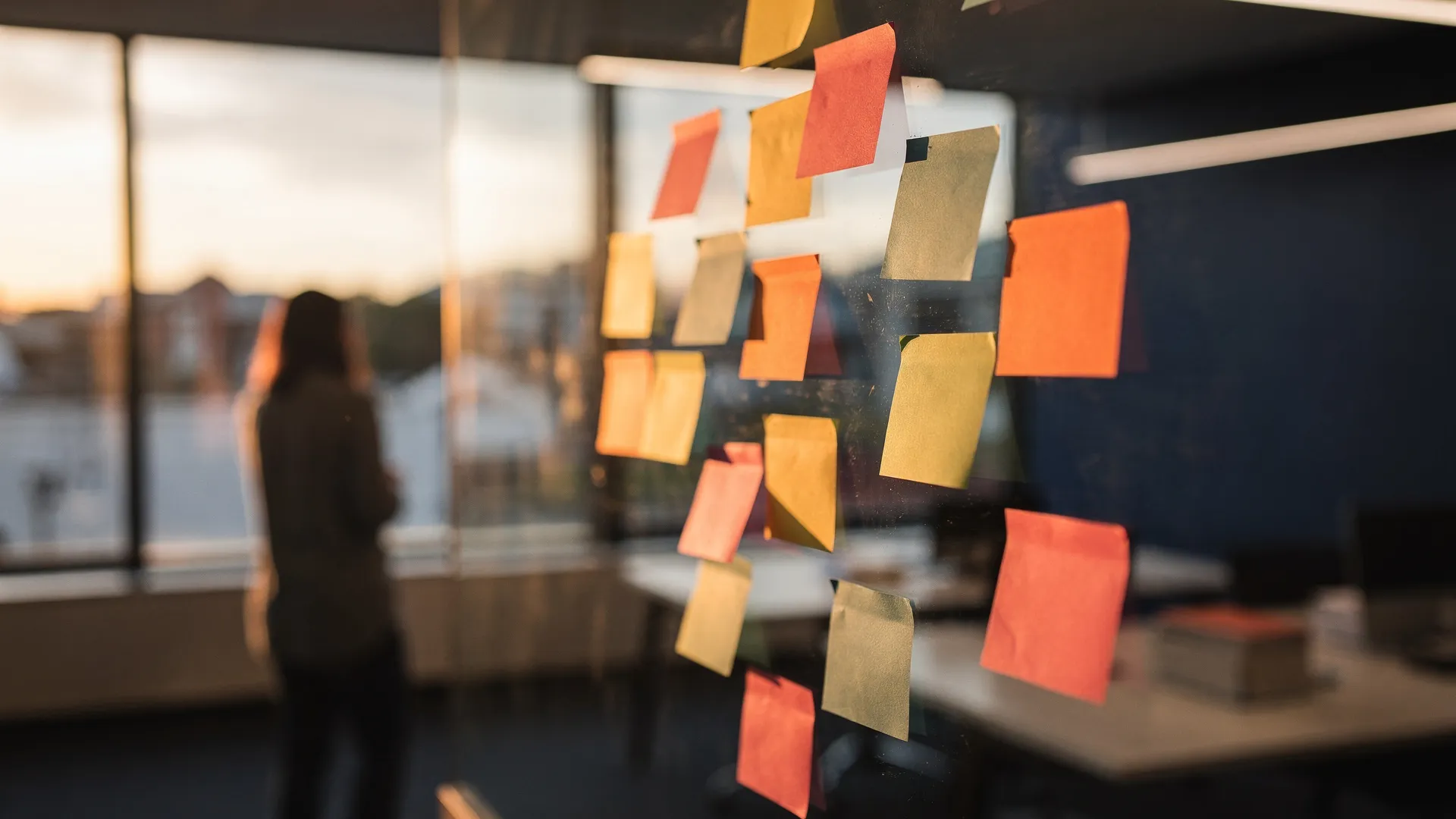 Sticky notes clustered on a glass wall in a research workshop